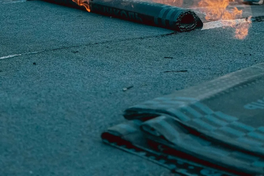 Roofing worker using a torch while installing dark roof membrane